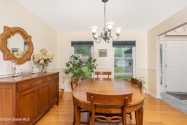 dining room with an inviting chandelier, baseboards, and light wood-type flooring