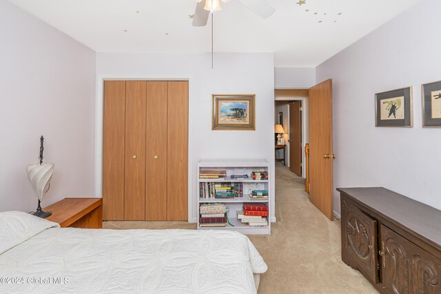 bedroom with light colored carpet, ceiling fan, and a closet