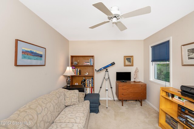 living room with baseboards, light carpet, and ceiling fan