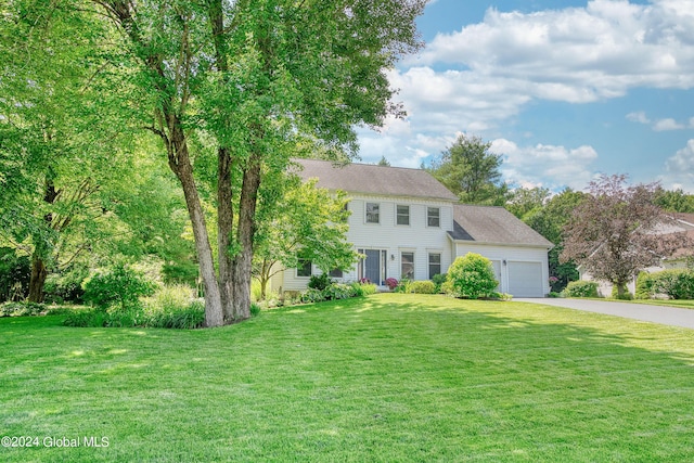 colonial house with roof with shingles, a garage, a front yard, and aphalt driveway