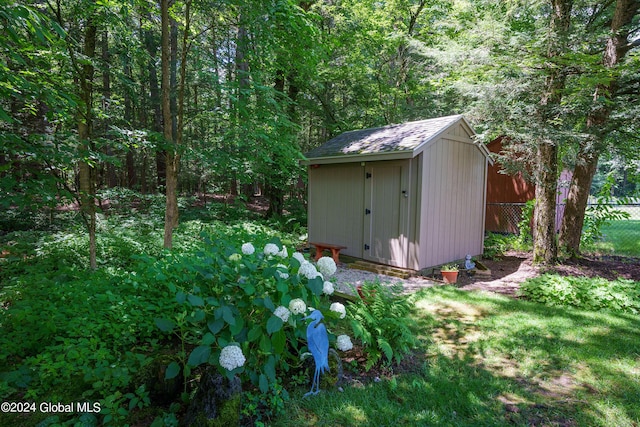 view of shed featuring fence and a view of trees