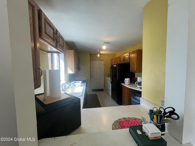 kitchen featuring black refrigerator, light tile patterned flooring, track lighting, and sink