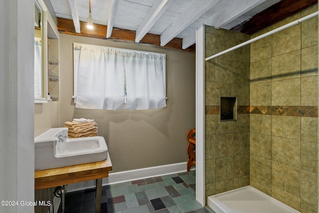 bathroom with tiled shower, beamed ceiling, and tile flooring