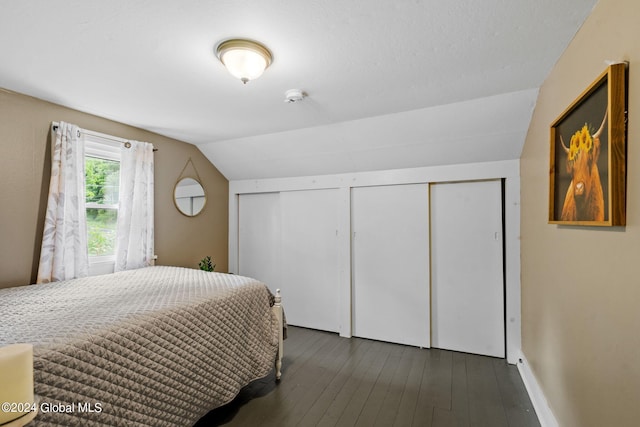 bedroom with multiple closets, vaulted ceiling, and dark wood-type flooring