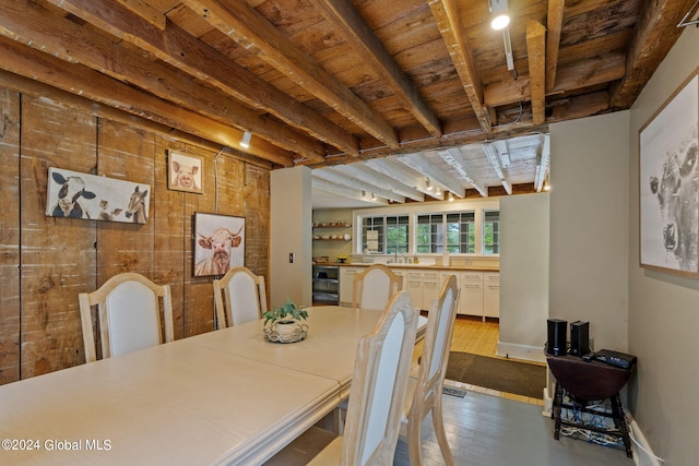 dining area with wooden walls, beam ceiling, hardwood / wood-style floors, and wood ceiling