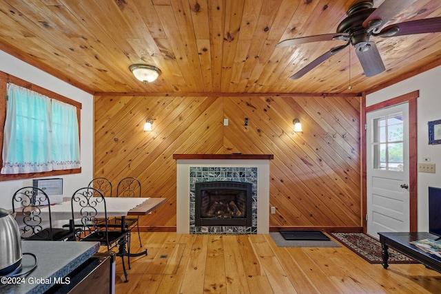 interior space featuring a fireplace, ceiling fan, wood walls, and light hardwood / wood-style flooring