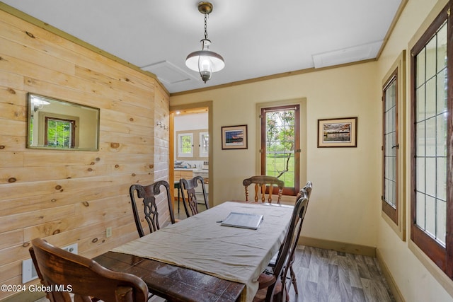 dining area featuring wood-type flooring, wooden walls, and ornamental molding