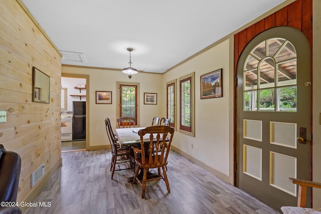 dining area with crown molding, wood walls, and hardwood / wood-style flooring