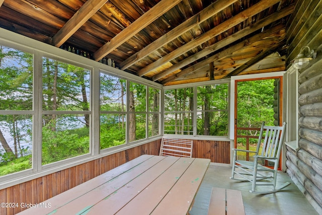 unfurnished sunroom featuring wooden ceiling, a wealth of natural light, and lofted ceiling with beams