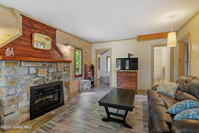 living room with hardwood / wood-style floors, wooden walls, a fireplace, and crown molding