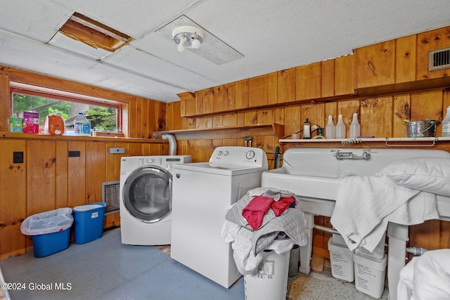 laundry area featuring separate washer and dryer and wood walls