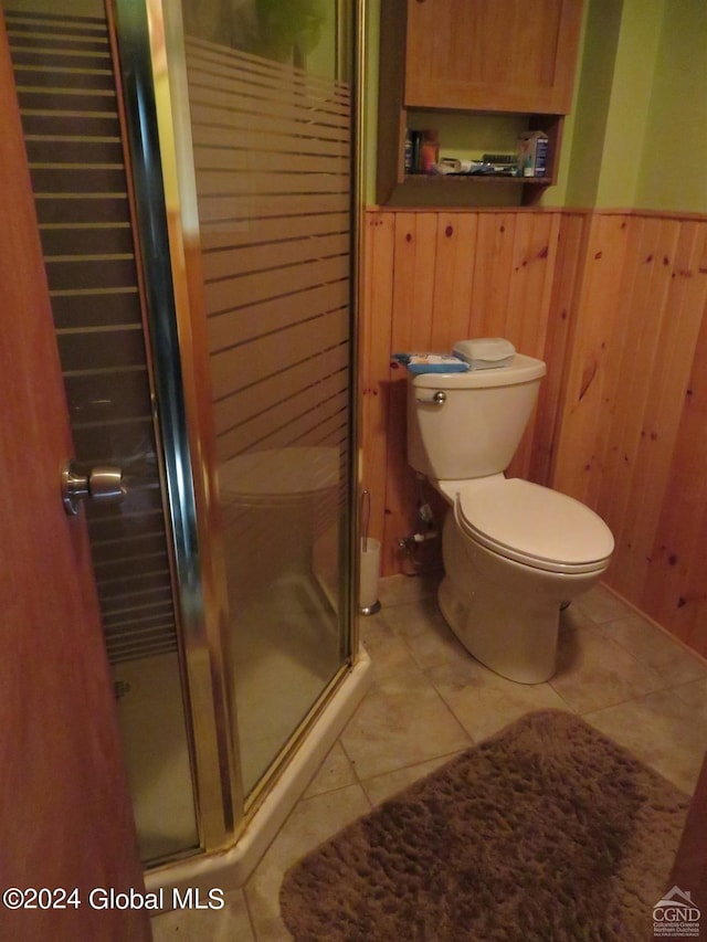 bathroom featuring walk in shower, tile flooring, wooden walls, and toilet