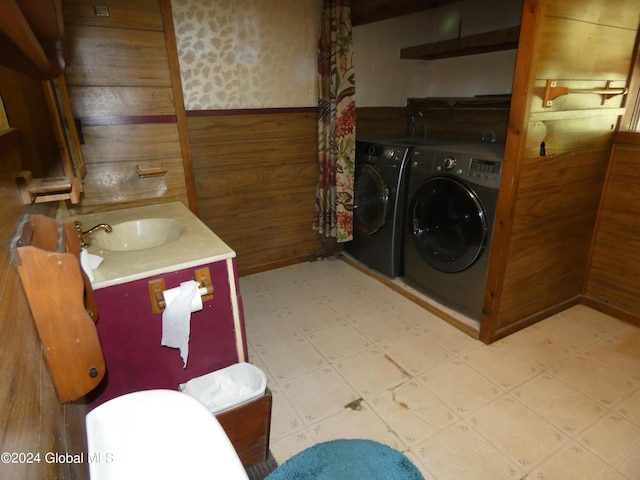 bathroom with vanity, wooden walls, and washing machine and clothes dryer