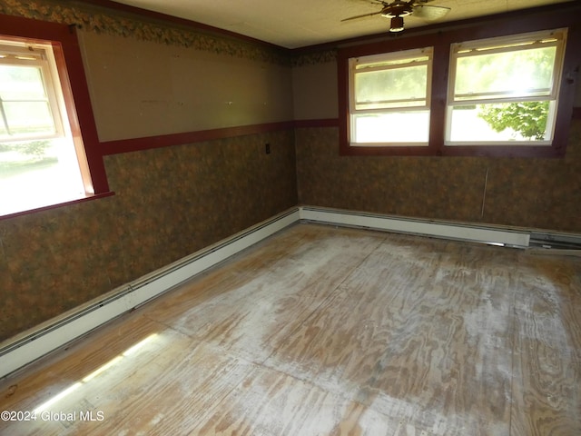 empty room with ceiling fan, plenty of natural light, and baseboard heating