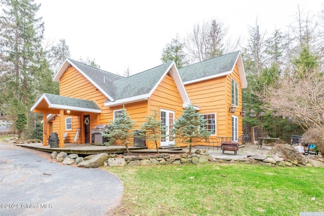 back of property with a fire pit, a lawn, french doors, and a patio area