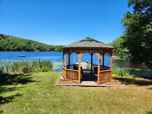 dock area with a water view, a gazebo, and a lawn