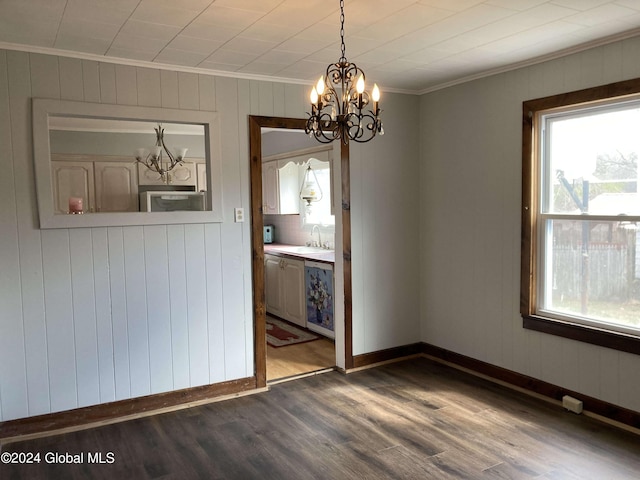 unfurnished room with dark wood-type flooring, ornamental molding, wooden walls, sink, and a notable chandelier