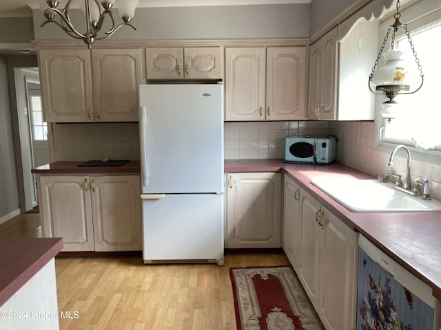 kitchen with hanging light fixtures, tasteful backsplash, white appliances, light hardwood / wood-style flooring, and sink