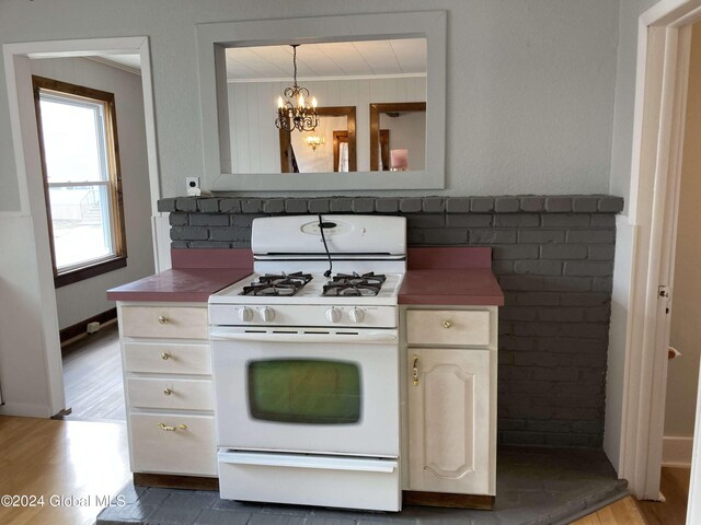 22 Lexington Ave, Gloversville, NY 12078 - kitchen featuring white gas range, ornamental molding, hanging light fixtures, light wood finished floors, and a notable chandelier