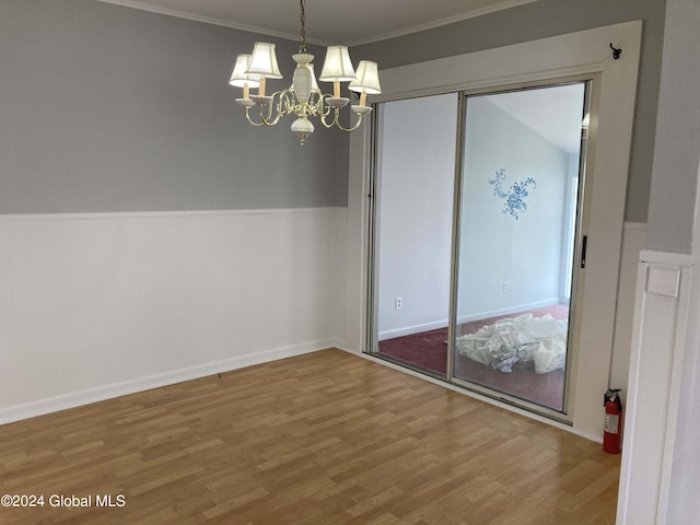 unfurnished dining area with an inviting chandelier, hardwood / wood-style floors, and crown molding