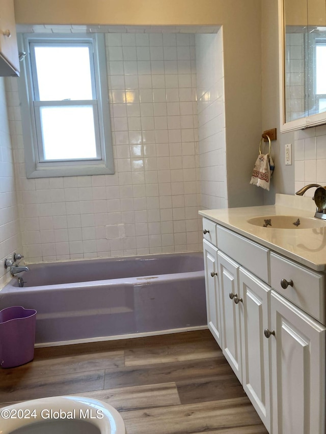 bathroom featuring wood-type flooring, vanity, and a tub