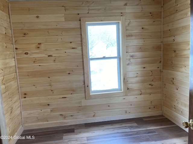 spare room featuring wood-type flooring, wood walls, and a wealth of natural light