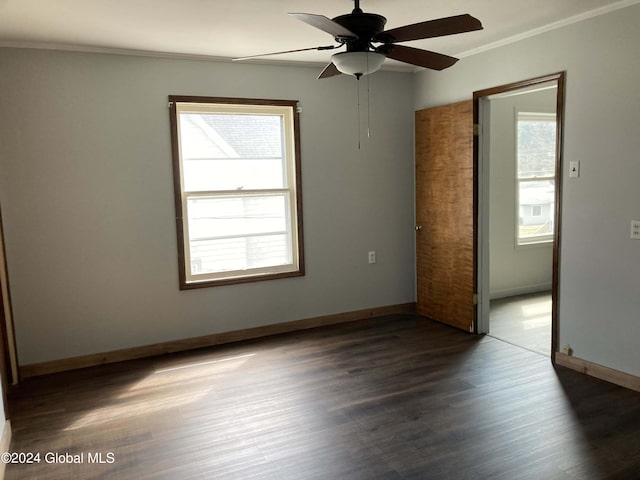 empty room with ornamental molding, dark hardwood / wood-style flooring, ceiling fan, and a wealth of natural light