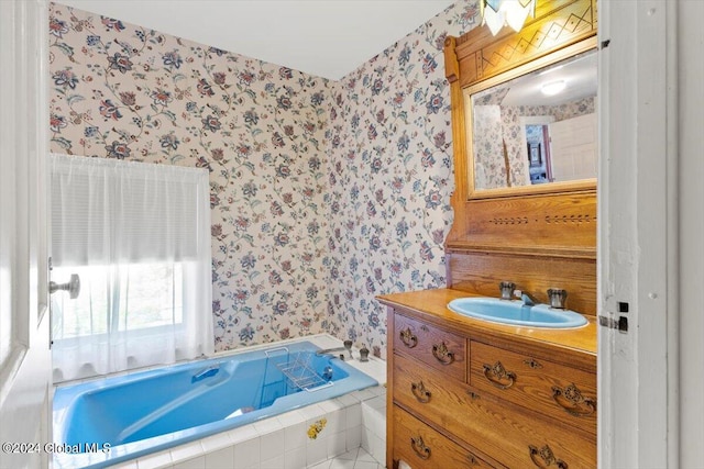 bathroom with tiled tub and vanity