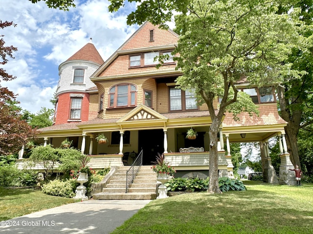 victorian house featuring a front lawn and covered porch