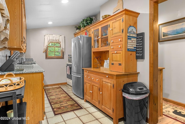 kitchen featuring lofted ceiling, stainless steel refrigerator, white range with electric cooktop, and light stone countertops