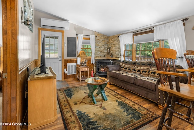 living room with a wall mounted AC, light hardwood / wood-style flooring, lofted ceiling, and a wood stove