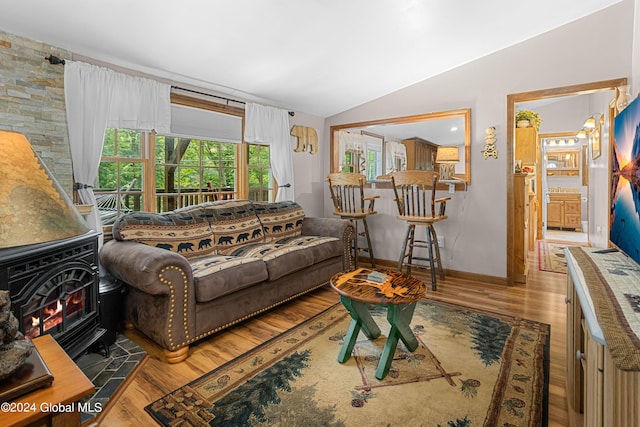 living room featuring lofted ceiling, wood-type flooring, and a wood stove