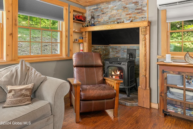 living area featuring dark hardwood / wood-style flooring, a wealth of natural light, an AC wall unit, and a wood stove