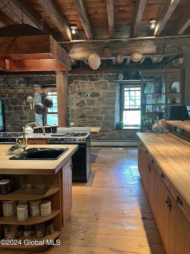 kitchen with black stove, sink, butcher block countertops, light hardwood / wood-style flooring, and beamed ceiling