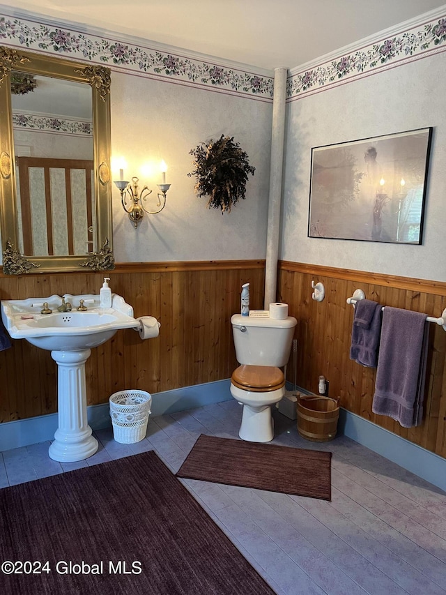 bathroom featuring tile patterned flooring, wooden walls, and toilet