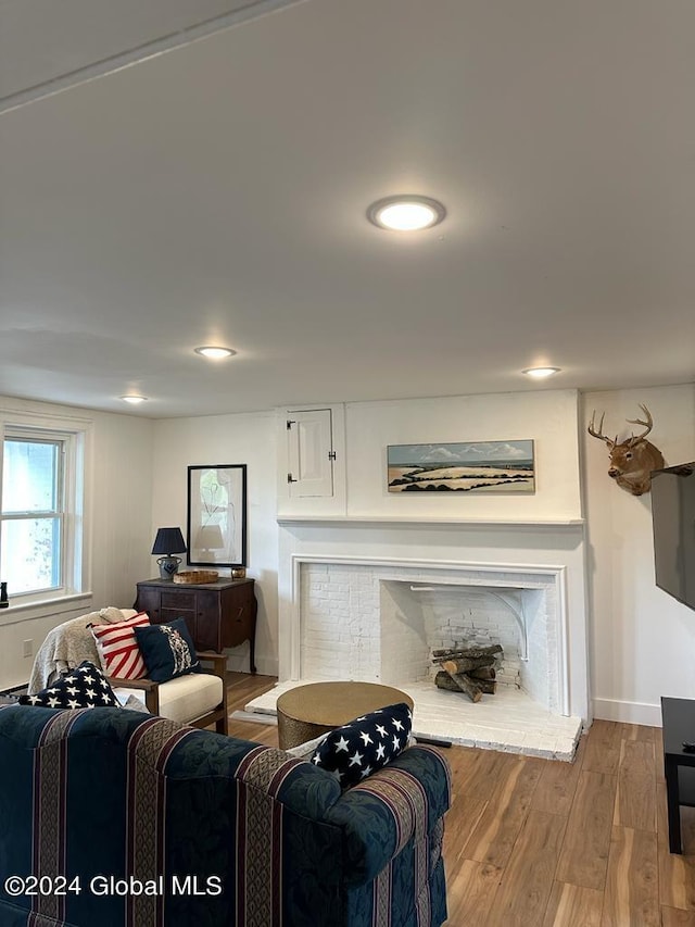 living room with a brick fireplace, baseboards, wood finished floors, and recessed lighting