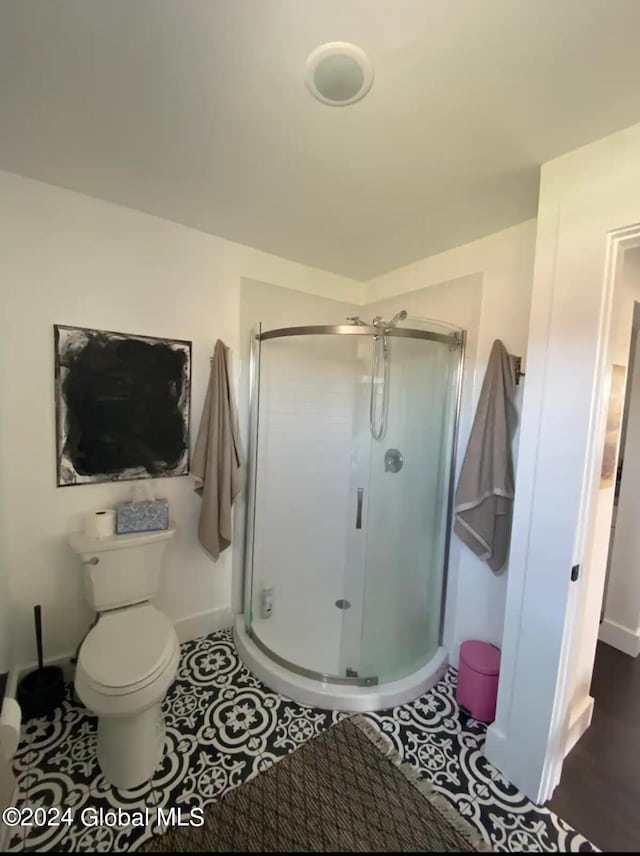 full bathroom featuring tile patterned flooring, baseboards, a shower stall, and toilet