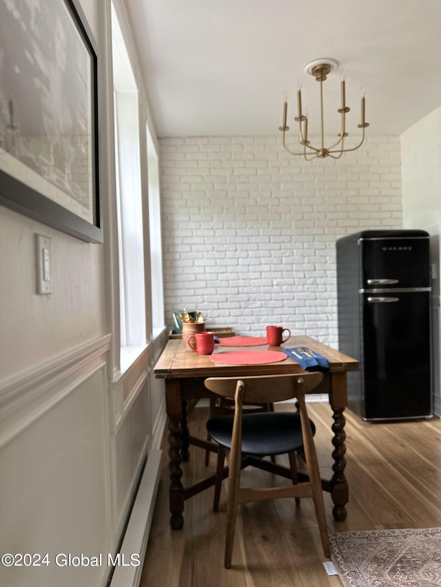 dining area featuring brick wall and wood finished floors