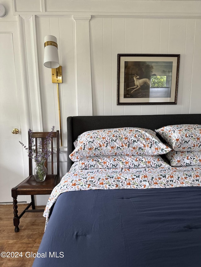 bedroom featuring a decorative wall and wood finished floors