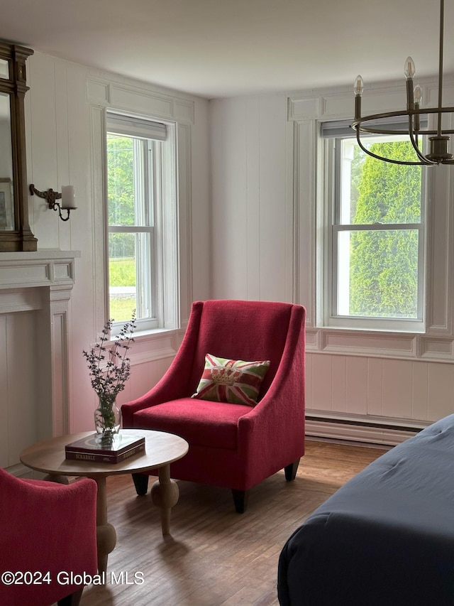 bedroom with a baseboard heating unit, multiple windows, wood finished floors, and a decorative wall