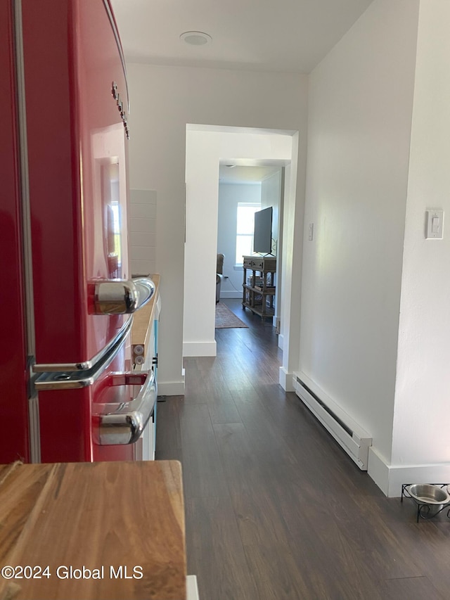 hall with a baseboard heating unit, dark wood-type flooring, and baseboards