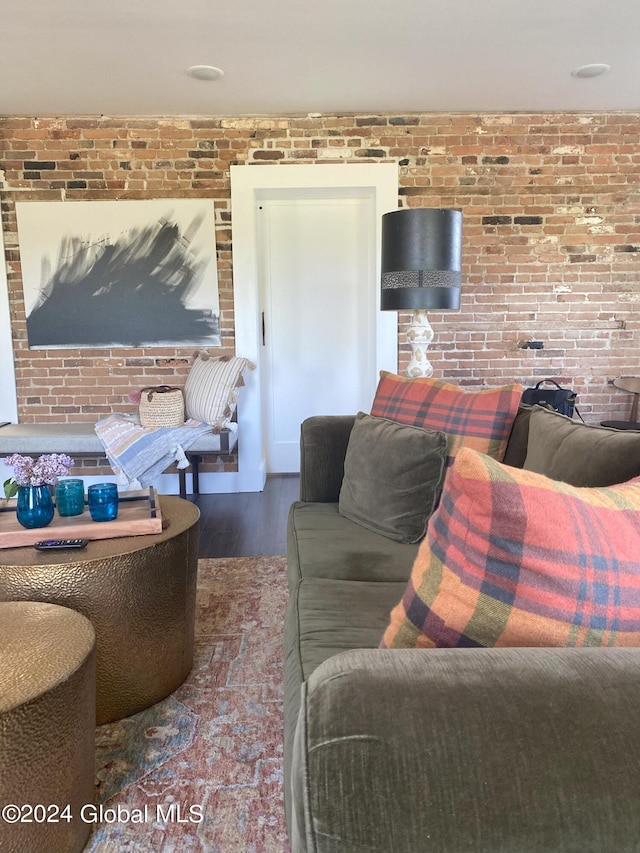 living area featuring brick wall and wood finished floors