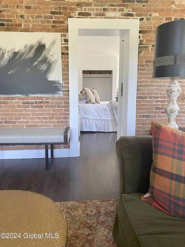 bedroom featuring brick wall and wood finished floors