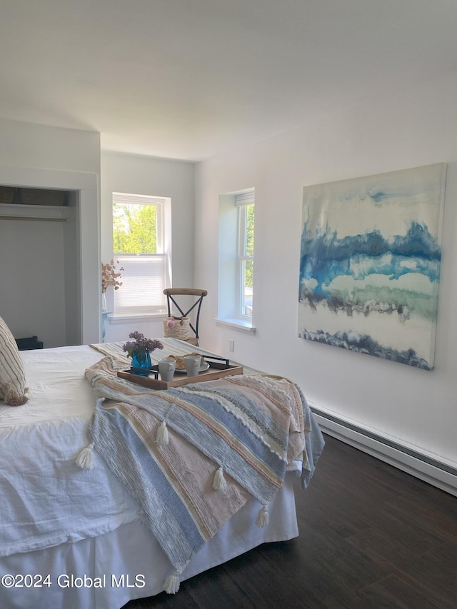 bedroom featuring a closet, baseboard heating, and wood finished floors