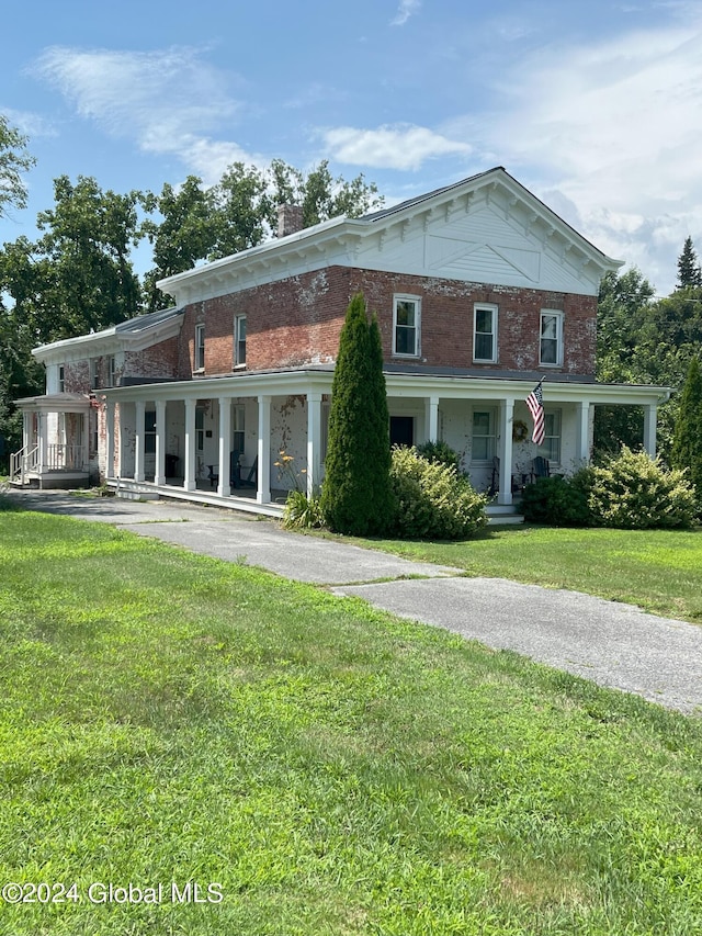 view of front facade featuring a porch, brick siding, a front lawn, and aphalt driveway