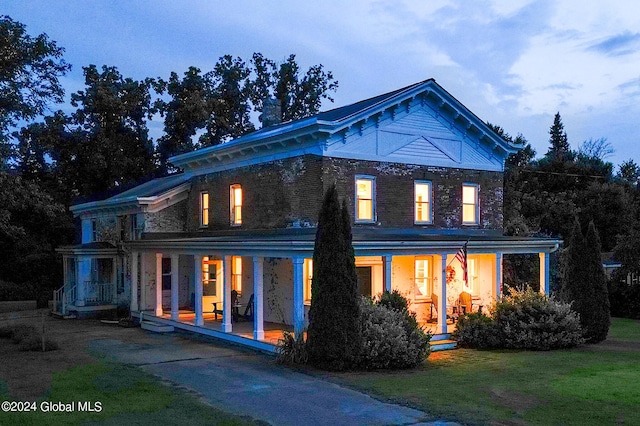 rear view of house with a porch and a lawn