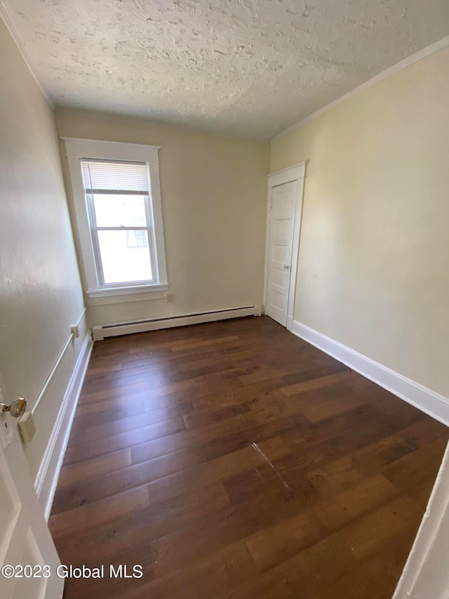 unfurnished room featuring a textured ceiling, ornamental molding, dark hardwood / wood-style floors, and a baseboard heating unit