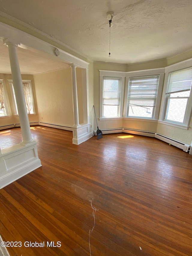 spare room featuring decorative columns, hardwood / wood-style flooring, and a healthy amount of sunlight