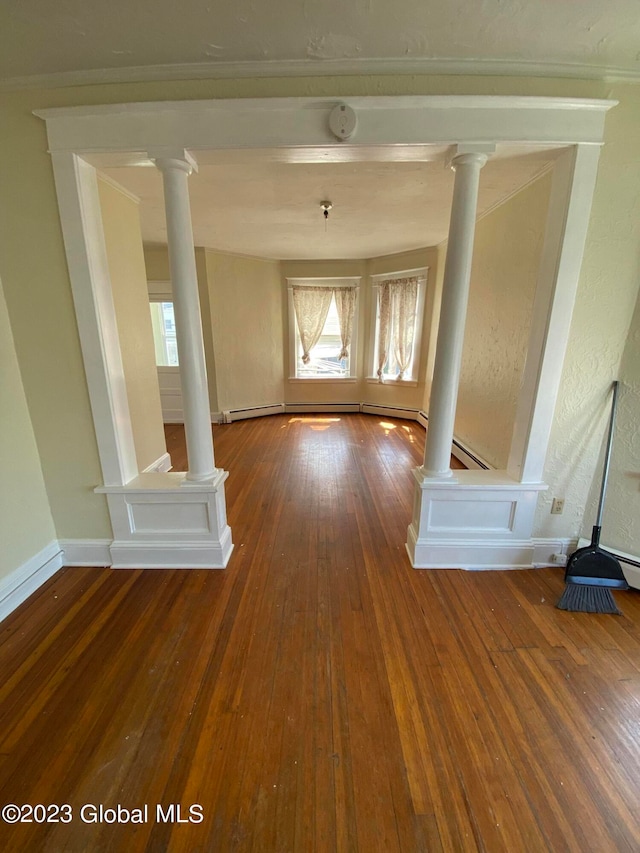 hallway with a baseboard heating unit, ornate columns, and hardwood / wood-style flooring