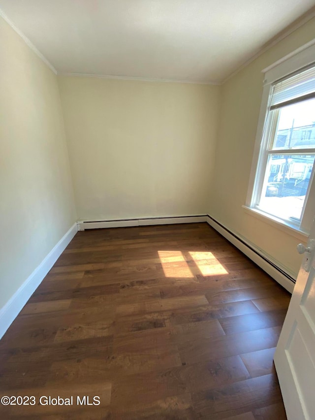 empty room with baseboard heating, wood-type flooring, and ornamental molding